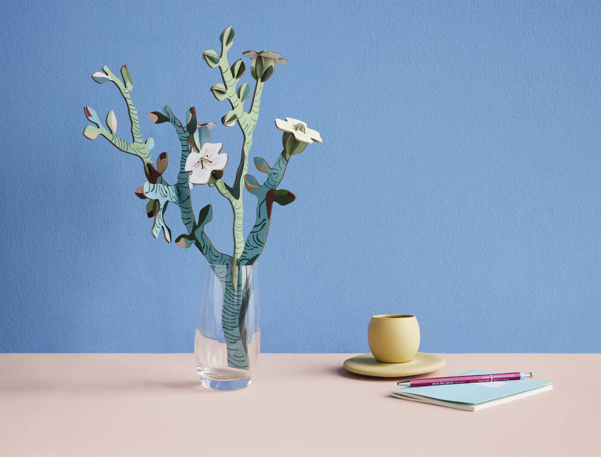 Van Gogh Almond Blossom cardboard bouquet in a glass vase on a desk with a cup and notebook